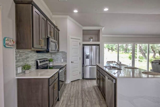 kitchen featuring stainless steel appliances, sink, ornamental molding, light hardwood / wood-style flooring, and decorative backsplash