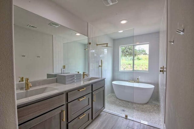 bathroom featuring hardwood / wood-style floors, vanity, and plus walk in shower