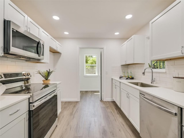 kitchen with appliances with stainless steel finishes, light wood-type flooring, plenty of natural light, and sink