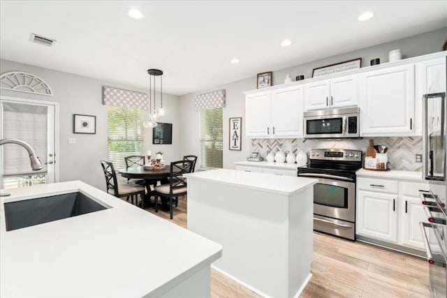 kitchen featuring white cabinetry, a center island, hanging light fixtures, tasteful backsplash, and appliances with stainless steel finishes