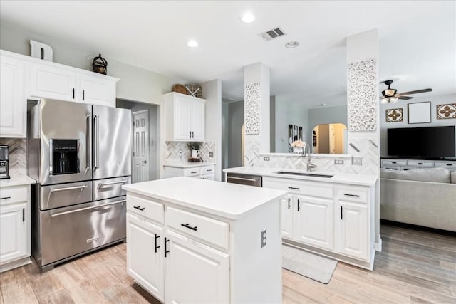 kitchen with a center island, backsplash, white cabinets, kitchen peninsula, and stainless steel appliances