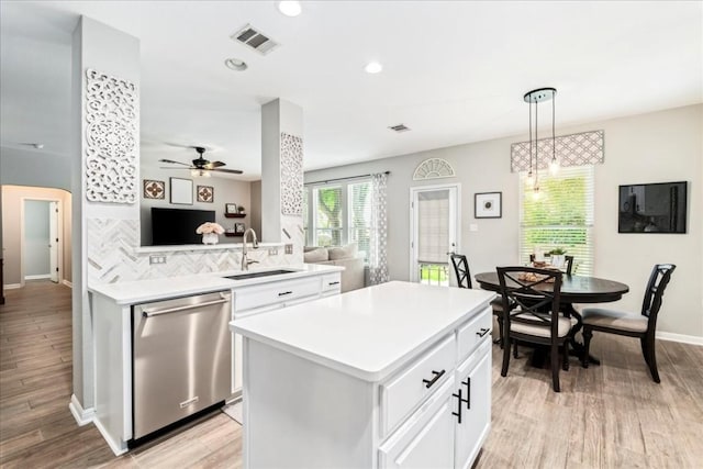 kitchen with backsplash, sink, stainless steel dishwasher, decorative light fixtures, and white cabinetry