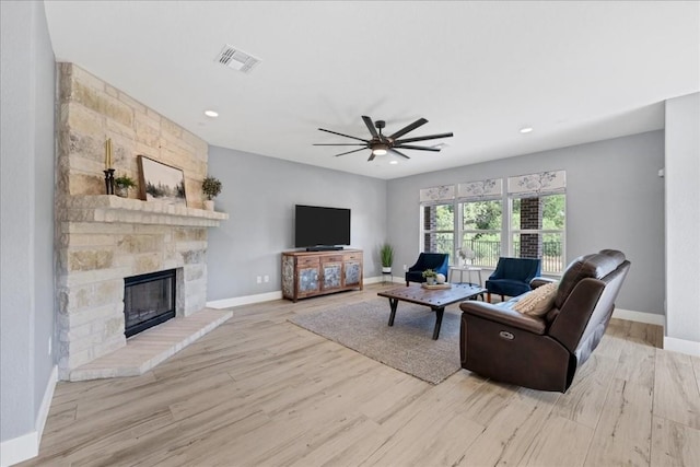 living room with ceiling fan, a fireplace, and light hardwood / wood-style flooring