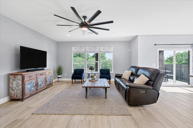 living room featuring ceiling fan, a wealth of natural light, and light hardwood / wood-style flooring