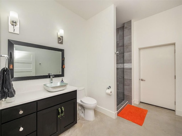 bathroom with a tile shower, vanity, and toilet