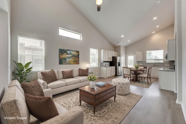 living room featuring ceiling fan, light hardwood / wood-style floors, and high vaulted ceiling