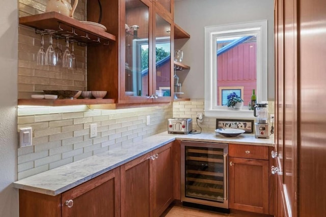 bar featuring light stone countertops, backsplash, and beverage cooler