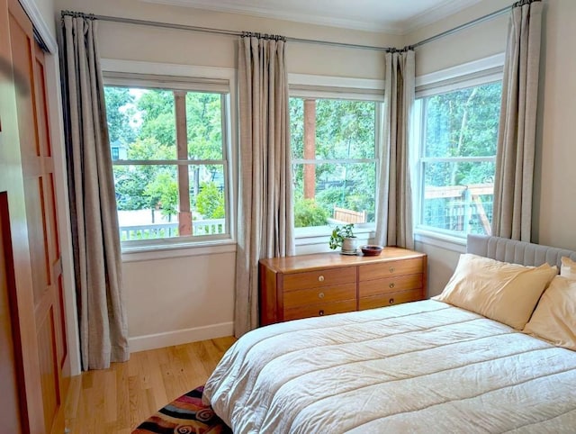 bedroom featuring multiple windows, light hardwood / wood-style floors, and ornamental molding