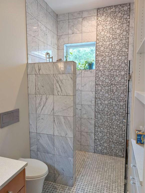 bathroom with vanity, toilet, and tiled shower