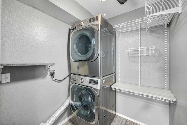 clothes washing area featuring hardwood / wood-style floors and stacked washer and clothes dryer