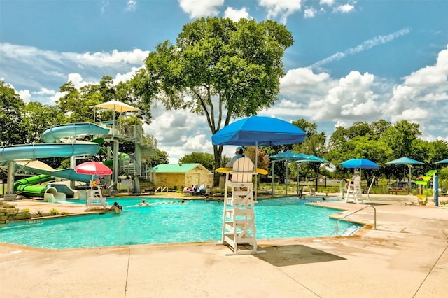 view of pool with a water slide and a patio area