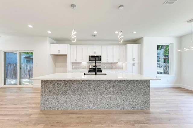 kitchen featuring pendant lighting, stainless steel appliances, and light hardwood / wood-style flooring