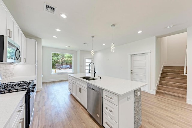 kitchen featuring sink, white cabinets, an island with sink, and appliances with stainless steel finishes