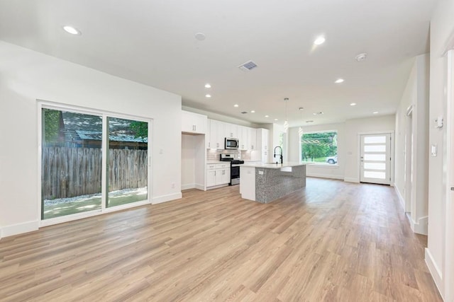 kitchen with pendant lighting, a center island with sink, light hardwood / wood-style flooring, white cabinetry, and stainless steel appliances