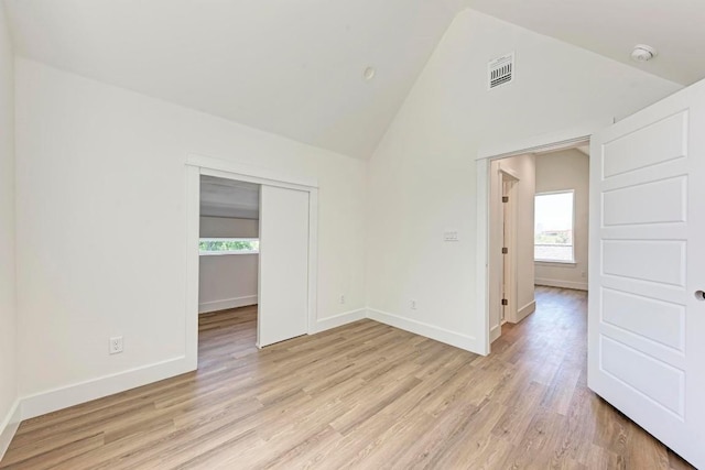 unfurnished room with high vaulted ceiling and light hardwood / wood-style floors