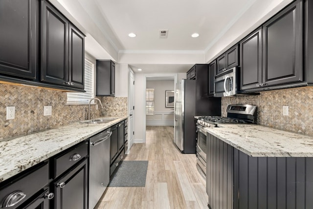 kitchen with light stone counters, decorative backsplash, stainless steel appliances, and light hardwood / wood-style flooring