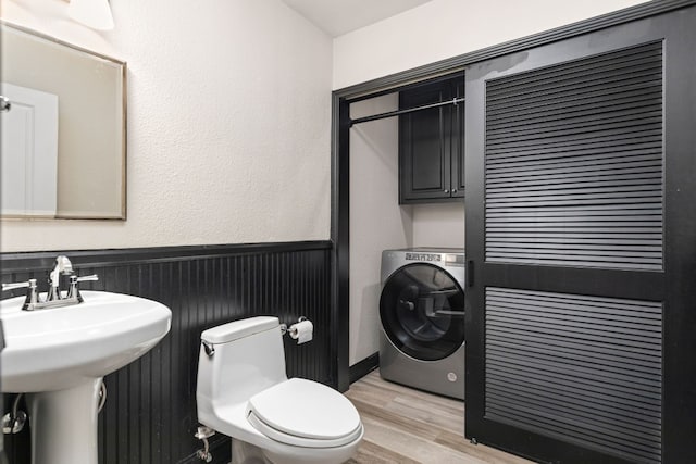 bathroom with sink, toilet, hardwood / wood-style flooring, and washer / dryer