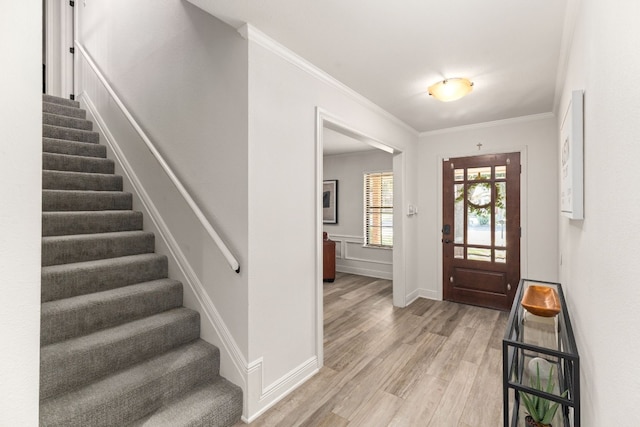 entryway featuring ornamental molding and light hardwood / wood-style flooring