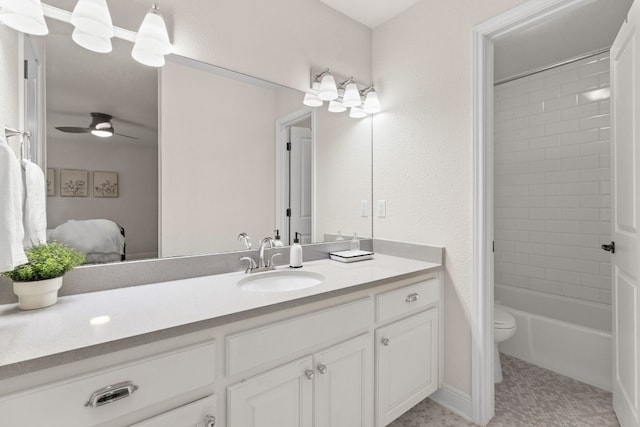 full bathroom with vanity, tiled shower / bath, ceiling fan, and toilet