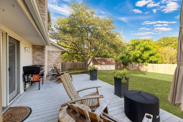 wooden terrace featuring a yard, area for grilling, and a storage unit