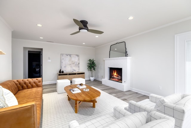 living room featuring a fireplace, ornamental molding, and light hardwood / wood-style flooring