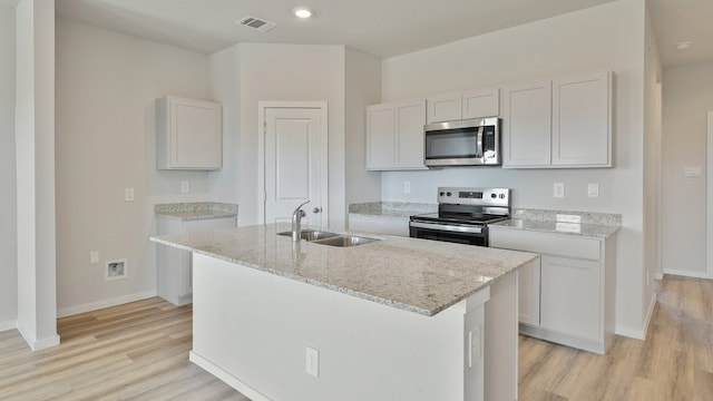 kitchen with a kitchen island with sink, white cabinets, sink, and stainless steel appliances