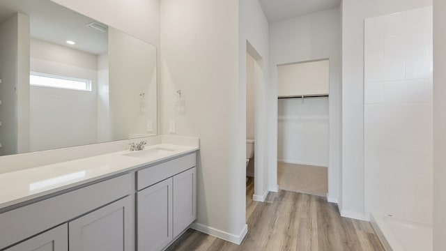 bathroom featuring toilet, a shower, vanity, and wood-type flooring