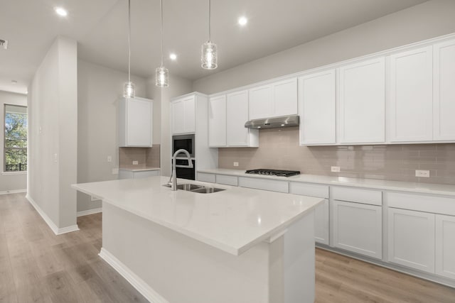 kitchen with white cabinetry, stainless steel gas stovetop, and a kitchen island with sink