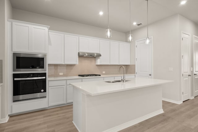 kitchen featuring sink, white cabinetry, oven, and an island with sink