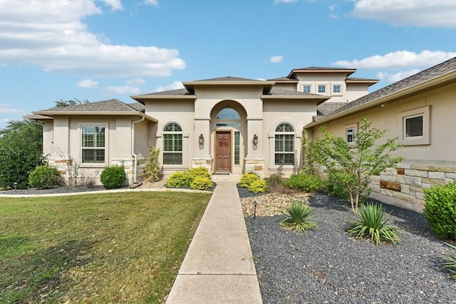 view of front facade featuring stone siding, a front yard, and stucco siding