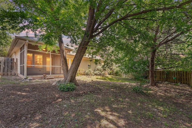 yard at dusk featuring a sunroom