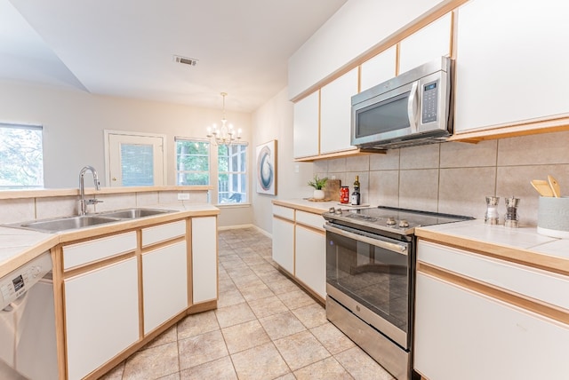 kitchen featuring pendant lighting, sink, appliances with stainless steel finishes, a notable chandelier, and white cabinetry