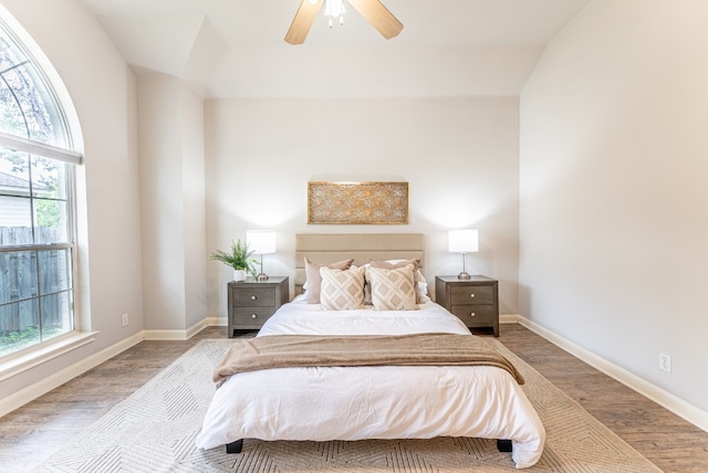 bedroom with light hardwood / wood-style flooring, multiple windows, lofted ceiling, and ceiling fan