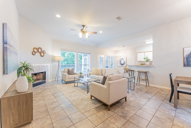 living room with ceiling fan with notable chandelier, light tile patterned flooring, and a fireplace