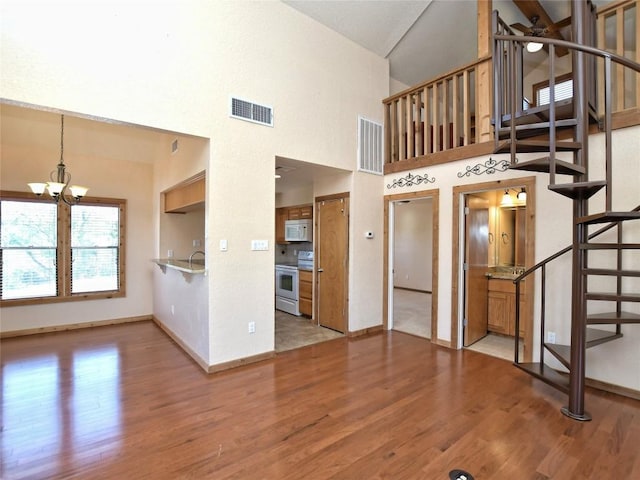 interior space featuring hardwood / wood-style floors, high vaulted ceiling, and an inviting chandelier