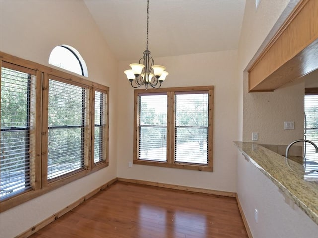 unfurnished dining area featuring a notable chandelier, lofted ceiling, and dark wood-type flooring