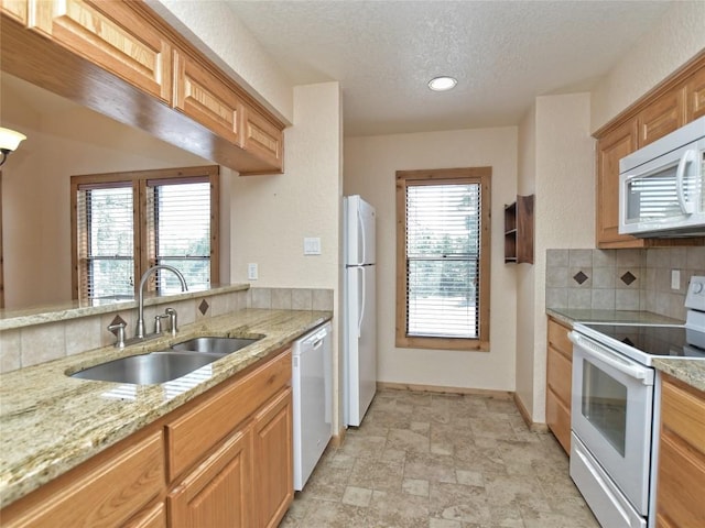 kitchen featuring white appliances, backsplash, a wealth of natural light, and sink