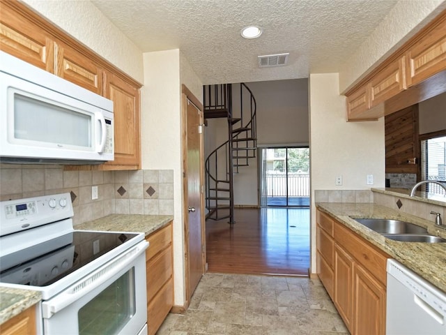 kitchen with a textured ceiling, sink, a healthy amount of sunlight, and white appliances