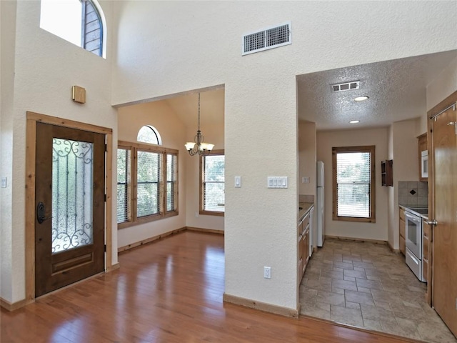 foyer entrance with an inviting chandelier, a textured ceiling, and light wood-type flooring