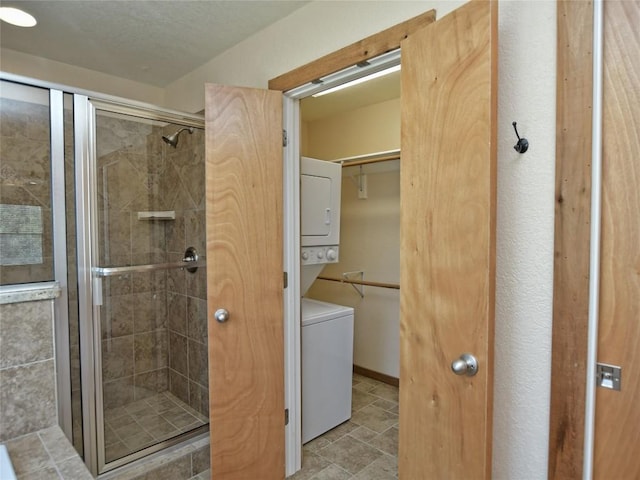 bathroom with stacked washing maching and dryer and an enclosed shower