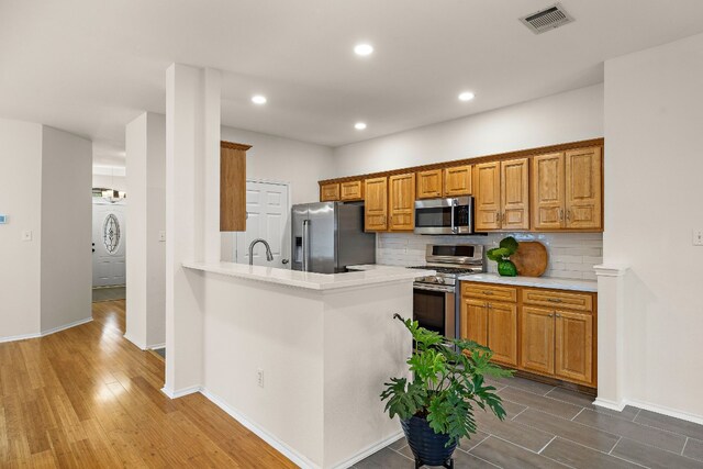 kitchen featuring kitchen peninsula, tasteful backsplash, washer / dryer, tile floors, and appliances with stainless steel finishes