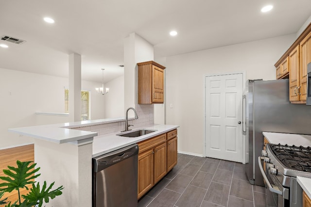 kitchen featuring an inviting chandelier, appliances with stainless steel finishes, backsplash, pendant lighting, and sink