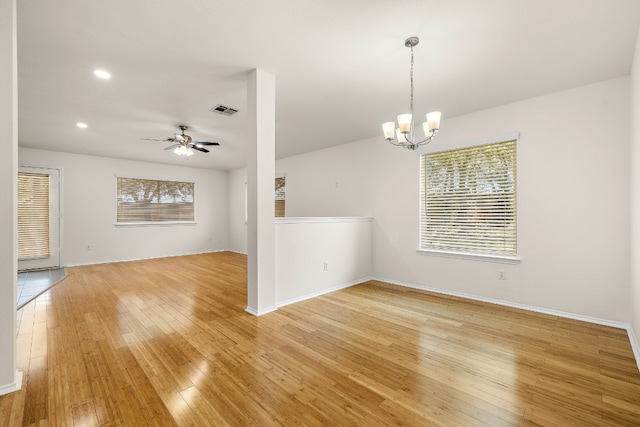 empty room with light hardwood / wood-style flooring and ceiling fan with notable chandelier