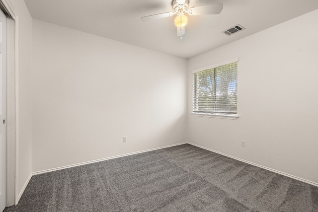 unfurnished room featuring ceiling fan and dark colored carpet