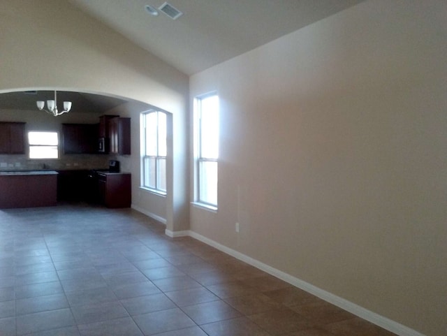 unfurnished living room featuring an inviting chandelier and light tile flooring