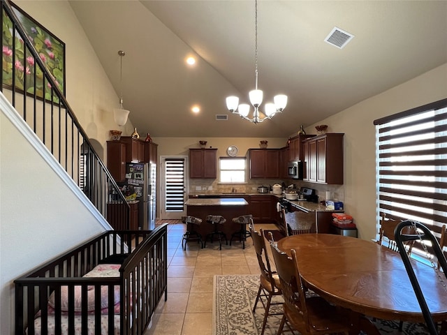 tiled dining space featuring a notable chandelier and vaulted ceiling