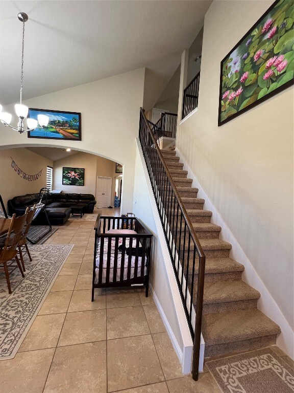 stairway featuring a notable chandelier, tile flooring, and a high ceiling