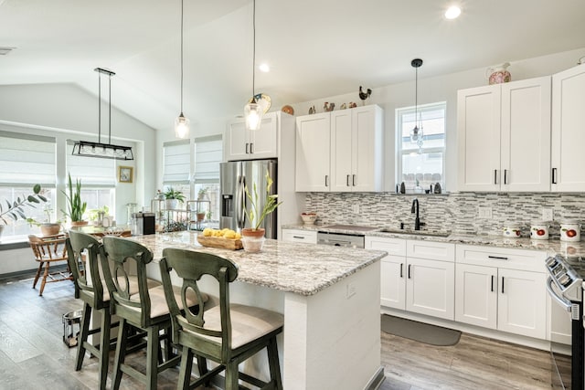 kitchen featuring appliances with stainless steel finishes, a center island, pendant lighting, white cabinets, and sink