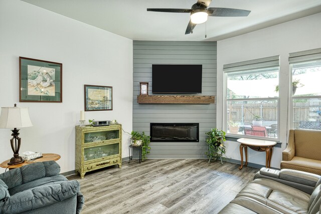 living room with a large fireplace, ceiling fan, and light hardwood / wood-style floors