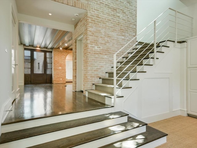 stairway featuring brick wall and carpet